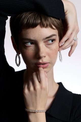 A MODEL LOOKING TO THE SIDE WITH HER ARM DRAPED OVER HER HEAD, AS SHE WEARS JEWELRY FROM NADRI’S TWINNIE COLLECTION