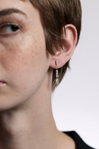 CLOSE UP OF HALF OF A MODEL’S FACE, AS SHE LOOKS TO THE SIDE AND WEARS THE TWINNIE FRONTBACK SHORT DROP EARRINGS 
