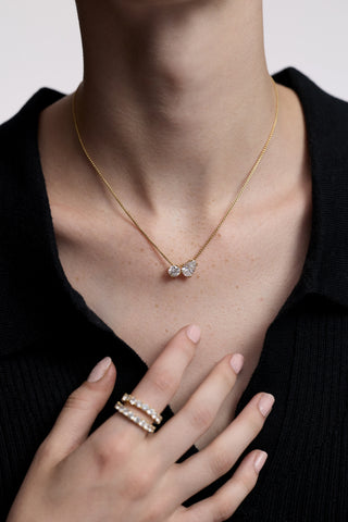 CLOSE UP OF A MODEL’S CHEST WITH HER HAND HELD UP TO HER NECKLINE, AS SHE WEARS A BLACK TOP AND THE TWINNIE TOI MOI PENDANT NECKLACE