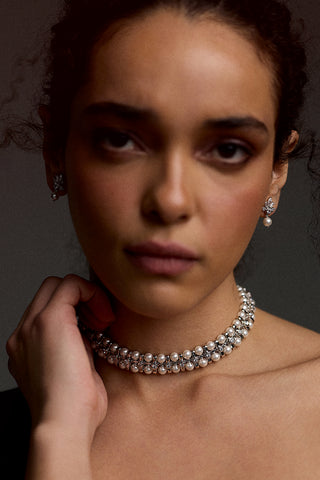 MODEL LOOKING AT THE CAMERA WITH HER HAND LIFTED UP TO HER NECK, WEARING THE UNDER THE SEA RETRO PEARL CHOKER NECKLACE