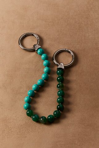 BON VOYAGE SEMI BEAD SWAG 3, WITH GREEN AND TURQUOISE STONES AND SILVER-TONED HARDWARE, AGAINST A BROWN BACKDROP