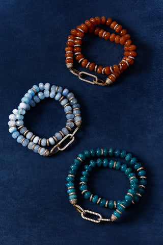 BOUJEE BEADS BLUE BRACELET, CARNELIAN BRACELET, AND LIGHT BLUE BRACELET, AGAINST A BLUE BACKGROUND