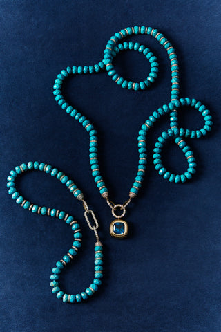 BOUJEE BEADS TURQUOISE BRACELET AND MATCHING LONG NECKLACE AGAINST A BLUE BACKDROP