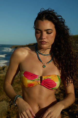 A MODEL IN A COLORFUL BATHING SUIT WEARING THE BOUJEE BEADS BLUE LONG NECKLACE AND MATCHING BRACELET