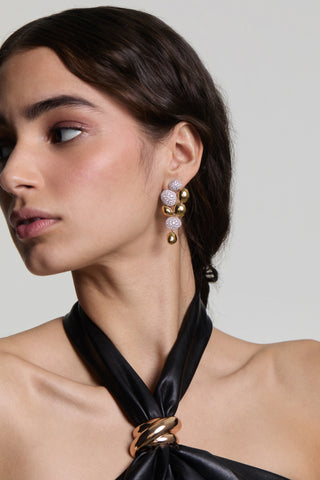 A MODEL LOOKING AWAY FROM THE CAMERA, WEARING THE PEBBLES LARGE DROP EARRINGS AND HER HAIR TUCKED BEHIND HER EAR