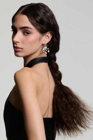 A MODEL LOOKING OVER SHOULDER WITH HER BACK TO THE CAMERA, WEARING THE PEBBLES CHANDELIER EARRINGS AND HER HAIR IN A LOOSE BRAID BEHIND HER