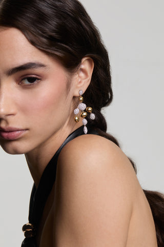 A MODEL LOOKING AT THE CAMERA WITH HALF OF HER FACE IN FRAME, WEARING THE PEBBLES CHANDELIER EARRINGS AND HER HAIR TUCKED BEHIND HER EAR