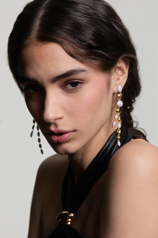 A MODEL LOOKING AT THE CAMERA WEARING THE PEBBLES FRONTBACK LINEAR EARRINGS WITH HER HAIR TUCKED BEHIND HER EAR