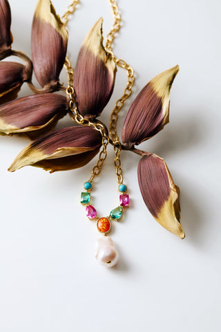 FRIEDA LONG NECKLACE DRAPED OVER A PURPLE LEAF