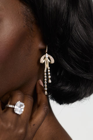 CLOSE-UP OF A MODEL’S EAR WEARING EROS PAVÉ BOW LEVERBACK EARRINGS, HAND LIFTED TO HER EAR WITH AN ENGAGEMENT RING