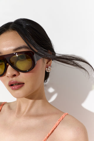 CLOSE UP OF A MODEL’S FACE WITH HER HAIR FLOWING FRAMING HER FACE, WEARING SUNGLASSES AND THE MOJITO BUTTON STUD EARRINGS