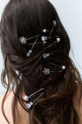 CLOSE UP OF THE BACK OF A WOMAN'S HEAD WITH BRUNETTE HAIR STYLED IN SOFT TWISTS AND WAVES, FEATURING VARIOUS CZ AND PEARL HAIR PINS FROM NADRI'S HAIR TODAY COLLECTION WOVEN THROUGHOUT THE HAIRSTYLE.