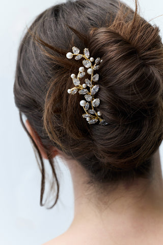 CLOSE-UP OF THE BACK OF A WOMAN’S HEAD WITH BRUNETTE HAIR STYLED IN A BUN, FEATURING NADRI’S VINE HAIR COMB PINNED INTO THE BUN