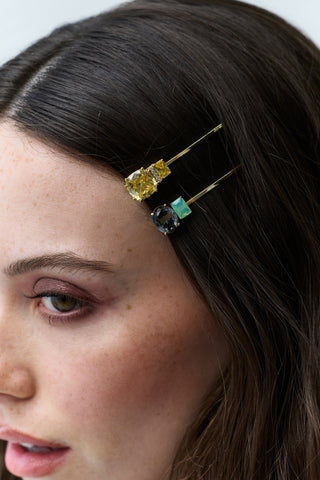 CLOSE UP OF THE SIDE OF A WOMAN'S HEAD WITH BRUNETTE HAIR, FEATURING A YELLOW AND GREEN BOBBY PIN FROM NADRI'S HAIR TODAY COLLECTION PINNING HER HAIR BACK.