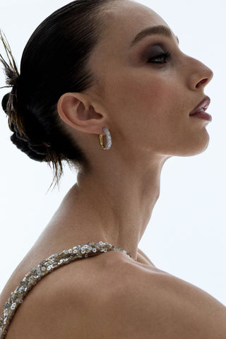 SIDE PROFILE OF A MODEL WITH A SPIKY SLICK-BACK BUN, WEARING A GOLD DRESS AND THE TURN UP THE VOLUME OVAL HOOP EARRINGS