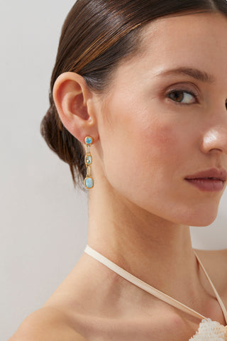 CLOSE UP OF MODEL WEARING CABARETE TRIPLE DROP MULTI EARRINGS LOOKING INTO THE CAMERA. HER HAIR IS IN A SLICK BACK BUN. 