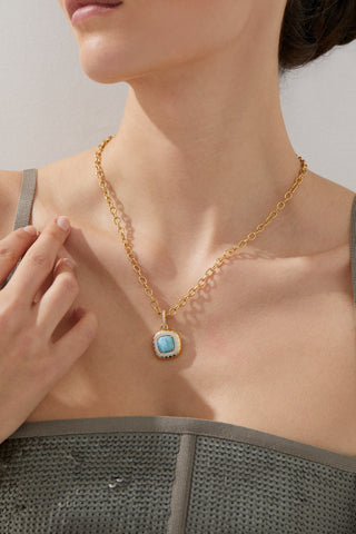 CABARETE LARIMAR LARGE PENDANT NECKLACE ON MODEL. IT IS A CLOSE UP IMAGE WITH HER FACE MOSTLY CROPPED OUT OF FRAME FOCUSING ON THE PENDANT NECKLACE WITH A SQUARE NECKLINE METALLIC SEQUIN DRESS. 