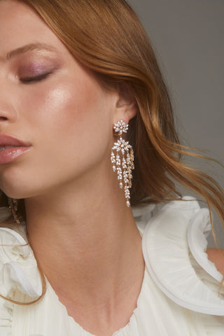 SAVANNAH DRAMA CZ CHANDELIER EARRINGS ON MODEL. HER EYES ARE CLOSED AND HAIR IS SWEPT BACK. SHE IS WEARING A WHITE RUFFLE TOP GIVING A ROMANTIC LOOK. 