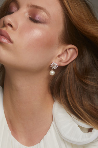 SAVANNAH PEARL CZ DROP EARRINGS ON MODEL. HER EYES ARE CLOSED AND HER HAIR IS BLOWING IN THE WIND. SHE IS WARING A PLEATED WHITE BLOUSE. 