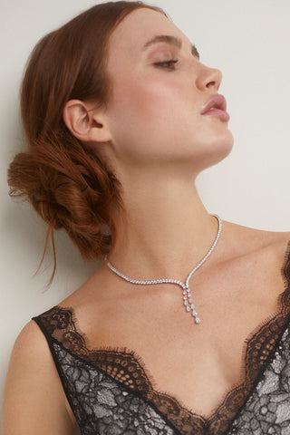 CLOSE UP IMAGE OF MODEL WEARING THE WILLOW ROUND CZ TENNIS DOUBLE DROP Y NECKLACE WITH A BLACK AND WHITE LACY TOP.  SHE IS LOOKING OFF TO THE SIDE AND HER HAIR IS IN A LOOSE BUN. 