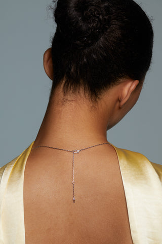 BACK VIEW OF CRUSHED HALO CROSS PENDANT NECKLACE ON MODEL SHOWING A DETAIL SHOT OF THE CLASP. MODELS HAIR IS UP IN A BUN AND OUT OF THE WAY FOR CLEAR VIEW OF NECKLACE CHAIN. 