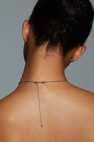 BACK VIEW OF MODEL WEARING CRUSHED PAVE FRONTAL NECKLACE. HER HAIR IS PULLED UP INTO A BUN WITH THE NECKLACE CHAIN IN CLEAR DETAIL SHOWING THE BOLO CLASP CLOSURE THAT IS ADJUSTABLE. 