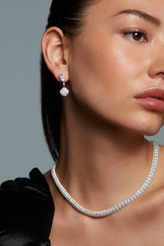 MODEL WEARING CRUSHED PAVE DOUBLE DROP EARRINGS. IT IS A CLOSE UP OF HER FACE AND NECKLINE (WEARING THE CRUSHED PAVE CZ COLLAR NECKLACE) HER HAIR IS PULLED BACK INTO A SLICK PONYTAIL.