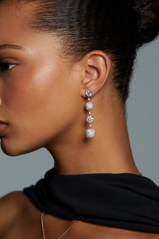 SIDE VIEW OF MODEL WEARING CRUSHED CUSHION LINEAR EARRINGS. HER HAIR IS PULLED BACK INTO A BUN AND SHE IS WEARING A SILK BLACK SCARF.