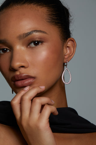 CLOSE UP ON MODEL WEARING CRUSHED TEARDROP LEVERBACK EARRINGS. HER HAND IS UP TO HER CHIN AND SHE IS LOOKING DIRECTLY INTO THE CAMERA. HAIR IS PULLED BACK INTO A BUN AND WEARING A BLACK SILK SCARF.