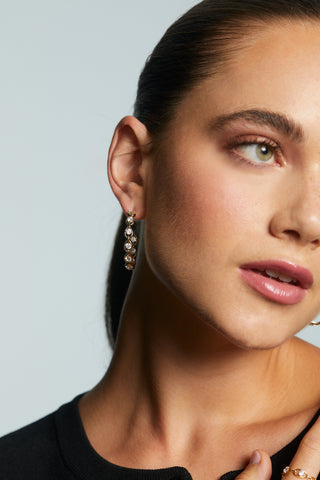 CLOSE UP OF IT GIRL MEDIUM C HOOP EARRINGS ON MODEL. 