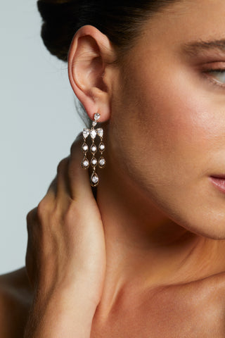 CLOSE UP OF MODEL WEARING IT GIRL CHANDELIER EARRINGS. 