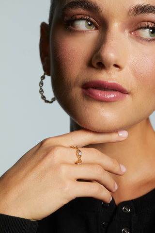 MODEL WEARING IT GIRL CHAIN RING. IT IS A CLOSE UP IMAGE OF HER HAND UP TO HER CHIN WITH HER FACE BLURRED IN THE BACKGROUND. 