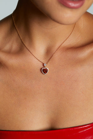 MODEL WEARING LE BISOU RED HALO HEART NECKLACE. IT IS A CLOSE UP IMAGE OF HER NECKLINE WITH A RED STRAPLESS DRESS ON.
