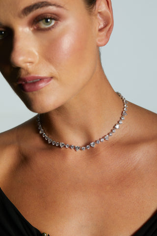 MODEL WEARING LE BISOU HEART COLLAR NECKLACE. IT IS A CLOSE UP SHOWING HER NECKLINE WITH FACE OUT OF FOCUS.