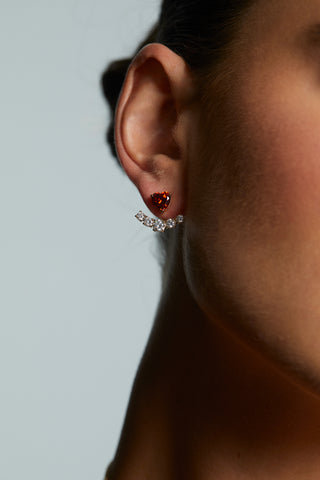 Close-up of a woman's ear, wearing LE BISOU RED HEART JACKET EARRINGS against a light gray background.