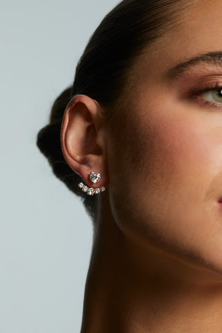 Close-up of a woman wearing LE BISOU HEART JACKET EARRINGS with a blurred background