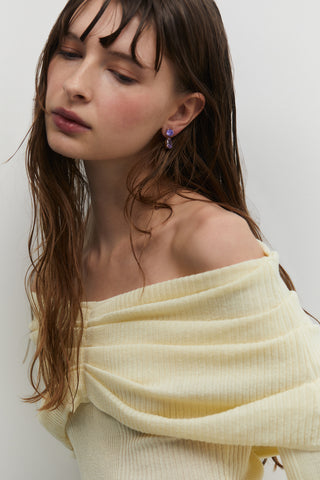 MID-TORSO SHOT OF A MODEL WEARING MAIDEN LV PEAR DROP EARRINGS WITH HER HAIR TUCKED BEHIND HER EAR AND A YELLOW TOP
