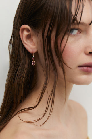 CLOSE UP OF A MODEL’S SIDE PROFILE WEARING MAIDEN PINK HALO OVAL LEVERBACK EARRINGS, WITH HER HAIR TUCKED BEHIND HER EAR.