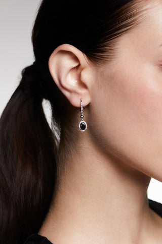 CLOSE UP OF A MODEL’S EAR, AS SHE WEARS A PONYTAIL AND THE MAIDEN BLACK HALO OVAL LEVERBACK EARRINGS