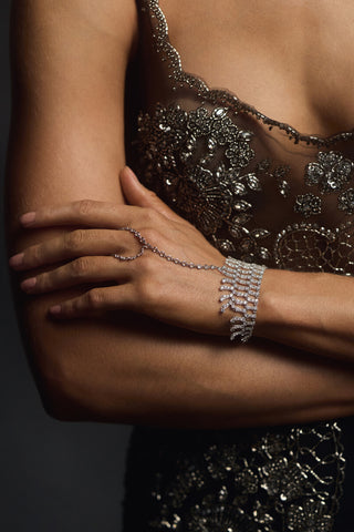 CLOSE UP OF A MODEL’S HAND WITH HER ARMS ARE CROSSED IN FRONT OF HER, AS SHE WEARS A BLACK SPARKLY DRESS AND THE FRANCES FRINGE HAND CHAIN BRACELET