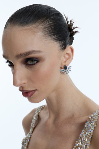 SIDE PROFILE OF A MODEL LOOKING SLIGHTLY UPWARD AS SHE WEARS HER HAIR IN A SLICK-BACK BUN, A GOLD SPARKLY DRESS, AND THE FRANCES BLUE FLARE STUD EARRINGS