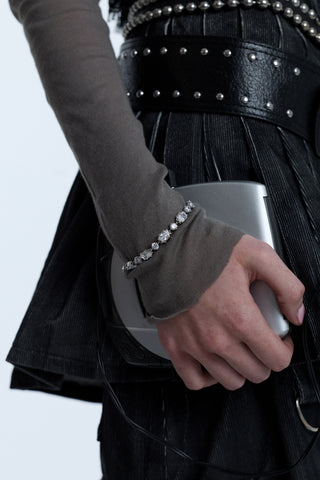 A MODEL’S WRIST AT HER SIDE, HOLDING A CD PLAYER WHILE WEARING A GRAY SHIRT AND THE SUPERNOVA LINE BRACELET LAYERED OVER THE SLEEVE
