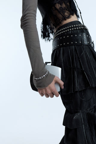 A SIDE VIEW OF A MODEL’S HIP AND HAND HOLDING A CD PLAYER, WEARING A GRUNGE OUTFIT WITH A STATEMENT BELT, A LONG-SLEEVE GRAY SHIRT, AND THE SUPERNOVA LINE BRACELET LAYERED OVER HER SLEEVE