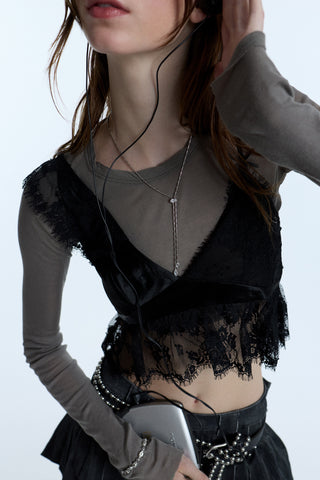 A MODEL’S TORSO IN A GRUNGE OUTFIT, WEARING THE SUPERNOVA LARIAT NECKLACE WHILE HOLDING A CD PLAYER AND LISTENING TO MUSIC THROUGH EARPHONES.