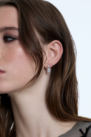 CLOSE UP OF A MODEL TURNED TO THE SIDE WITH HER BANGS IN FRONT OF HER FACE WEARING THE SUPERNOVA SMALL DROP EARRINGS