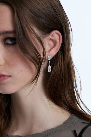 CLOSE UP OF THE SIDE OF A MODEL’S FACE WITH HER BANGS IN FRONT OF HER AND WEARING THE SUPERNOVA LARGE DROP EARRINGS