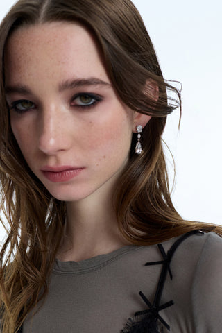 A MODEL LOOKING AT THE CAMERA, WEARING EYELINER AND THE SUPERNOVA LARGE DROP EARRINGS, WITH HER HAIR BLOWING AWAY FROM HER FACE