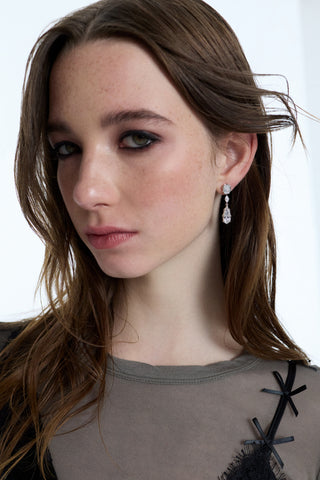 A MODEL LOOKING AT THE CAMERA, WEARING EYELINER AND THE SUPERNOVA LARGE DROP EARRINGS, WITH HER HAIR BLOWING AWAY FROM HER FACE