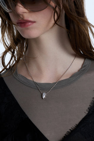 CLOSE UP OF A MODEL’S CHEST WEARING A GRAY SHIRT, A BLACK LACE TANK TOP, AND THE SUPERNOVA PENDANT NECKLACE LAYERED OVER THE TOP OF THE TWO