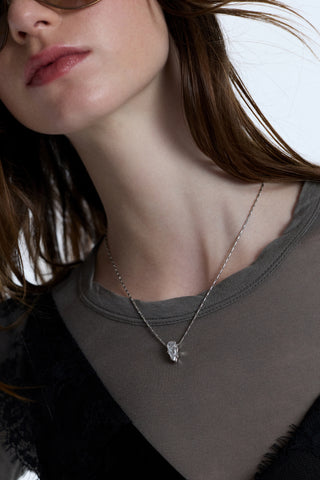 CLOSE UP OF A MODEL’S CHEST WEARING A GRAY SHIRT, A BLACK LACE TANK TOP, AND THE SUPERNOVA PENDANT NECKLACE LAYERED OVER THE TOP OF THE TWO